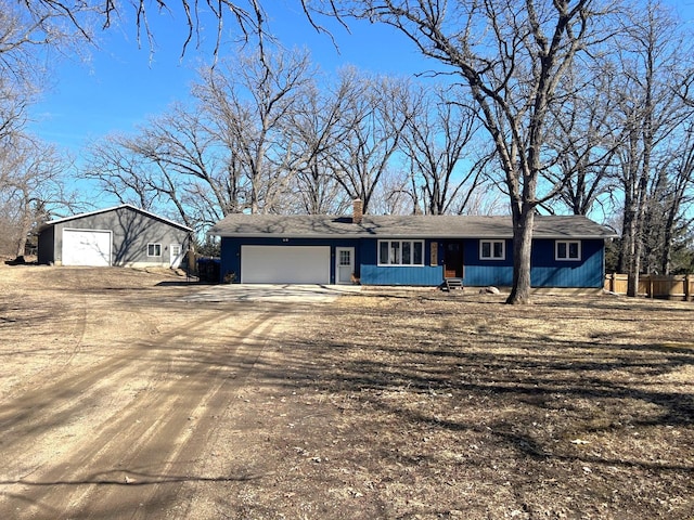 single story home featuring an attached garage, dirt driveway, and a chimney