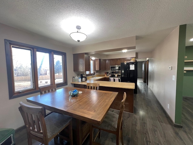 dining room featuring baseboards, a textured ceiling, and dark wood-style floors