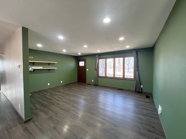 unfurnished living room with recessed lighting, a textured ceiling, dark wood-type flooring, and baseboards