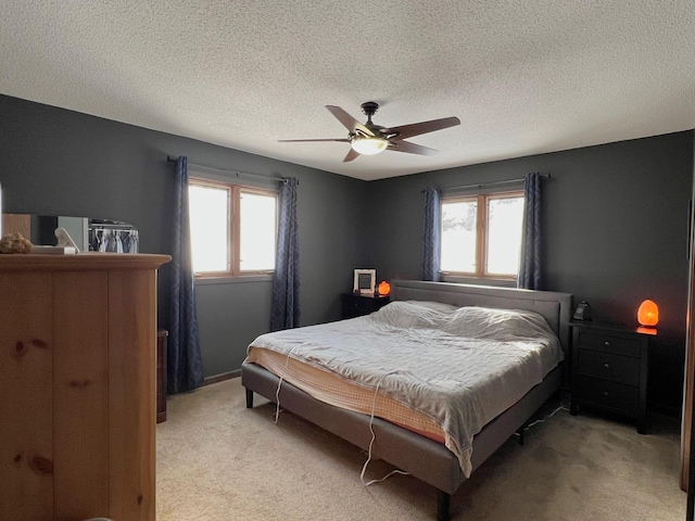 bedroom featuring light colored carpet, a ceiling fan, and a textured ceiling