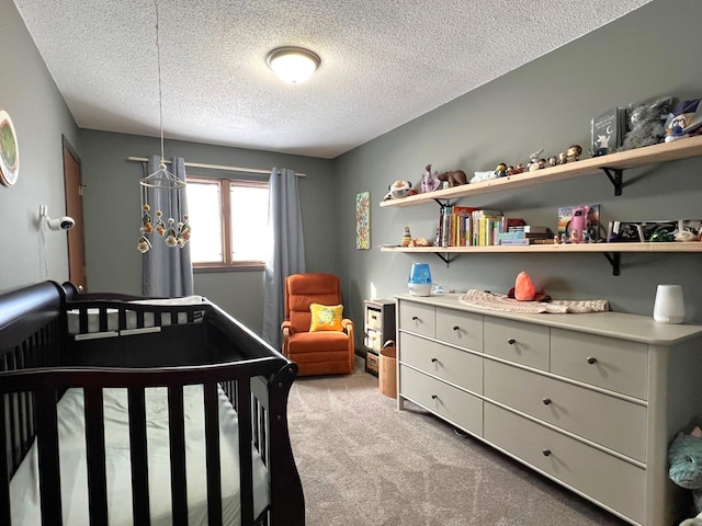 bedroom with a nursery area, light colored carpet, and a textured ceiling