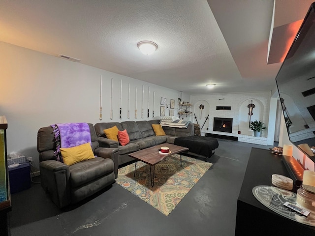 living room featuring a brick fireplace, visible vents, concrete flooring, and a textured ceiling