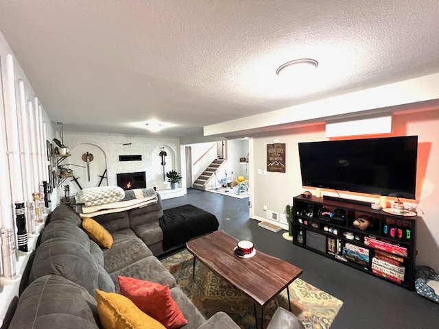 living area with stairway, a textured ceiling, a large fireplace, and finished concrete floors