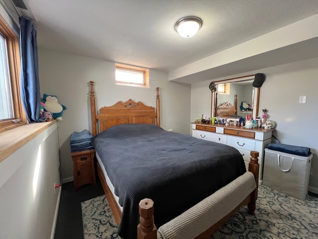 bedroom with light colored carpet, baseboards, and a textured ceiling