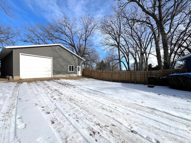 exterior space with a detached garage, an outbuilding, and fence