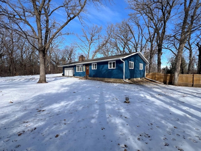 view of front of home featuring a chimney, a garage, and fence