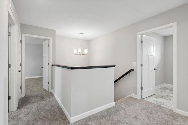 corridor with light colored carpet and a chandelier