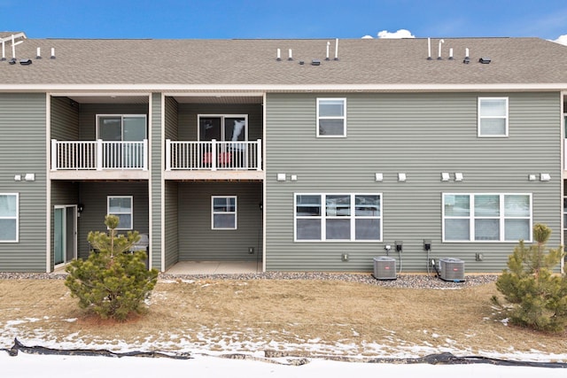 snow covered rear of property featuring central air condition unit