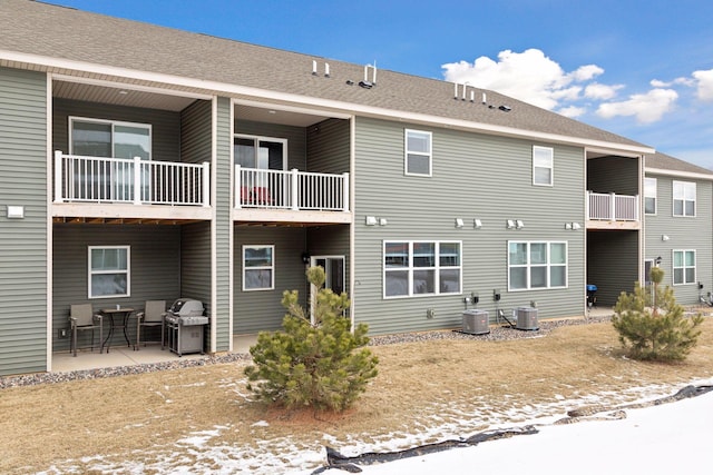 snow covered property featuring central AC unit and a patio area