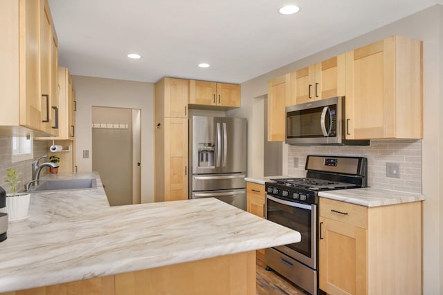 kitchen featuring appliances with stainless steel finishes, light countertops, a sink, and light brown cabinetry