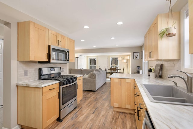 kitchen with stainless steel appliances, open floor plan, light countertops, and light brown cabinetry