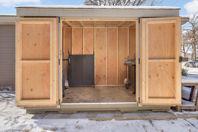 snow covered structure with an outbuilding