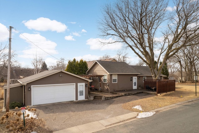 single story home featuring roof with shingles, a detached garage, a deck, and an outdoor structure