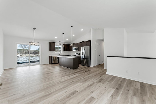 kitchen featuring sink, appliances with stainless steel finishes, a kitchen island, decorative light fixtures, and light wood-type flooring