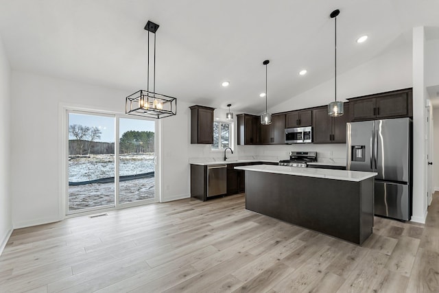 kitchen featuring stainless steel appliances, a center island, a wealth of natural light, and decorative light fixtures