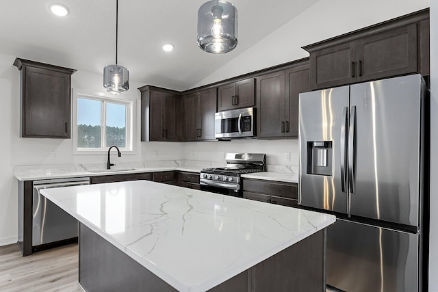 kitchen with sink, a center island, vaulted ceiling, appliances with stainless steel finishes, and pendant lighting