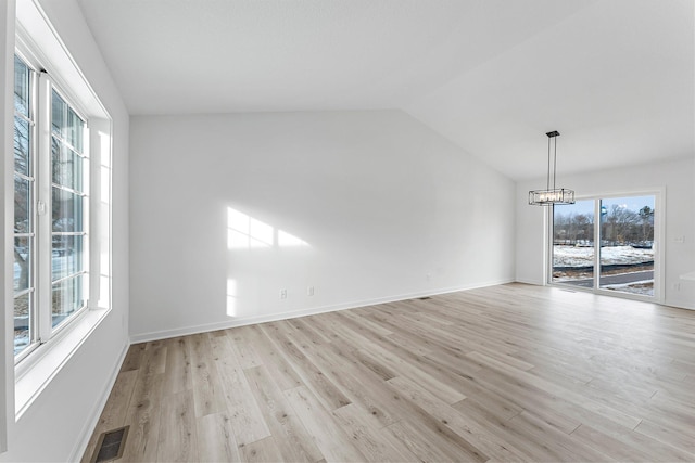 spare room with lofted ceiling, a chandelier, and light wood-type flooring