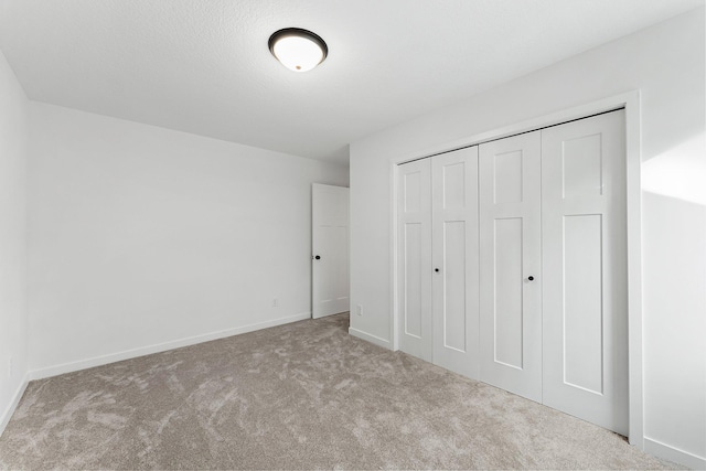 unfurnished bedroom featuring light colored carpet and a closet