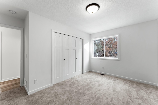 unfurnished bedroom with carpet floors, a closet, and a textured ceiling