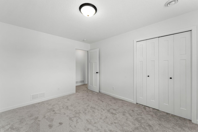 unfurnished bedroom featuring light carpet and a closet