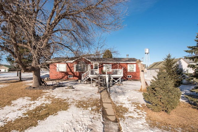 snow covered back of property featuring a deck