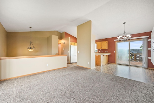 unfurnished living room featuring light colored carpet, vaulted ceiling, and a notable chandelier