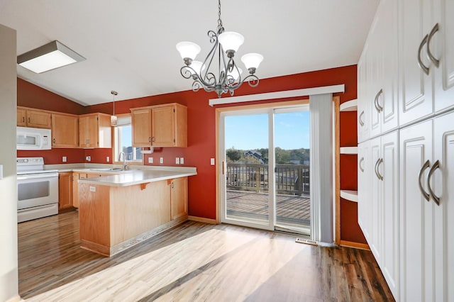 kitchen with a wealth of natural light, lofted ceiling, a kitchen bar, hanging light fixtures, and white appliances