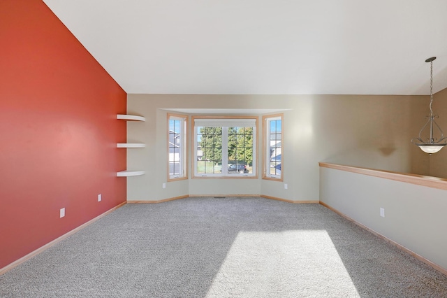 carpeted spare room featuring vaulted ceiling