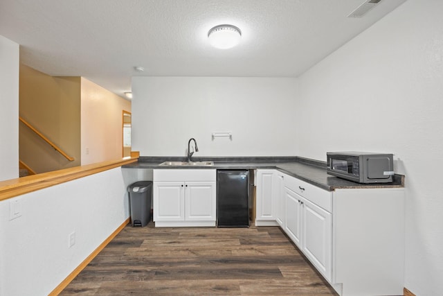 kitchen with refrigerator, white cabinetry, sink, kitchen peninsula, and dark wood-type flooring