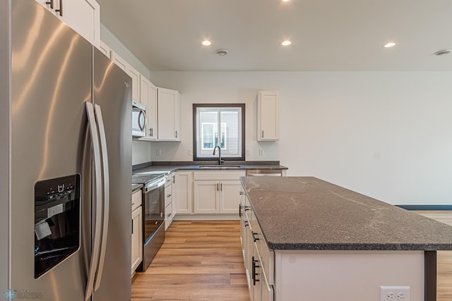 kitchen featuring a kitchen island, white cabinetry, sink, stainless steel appliances, and light wood-type flooring