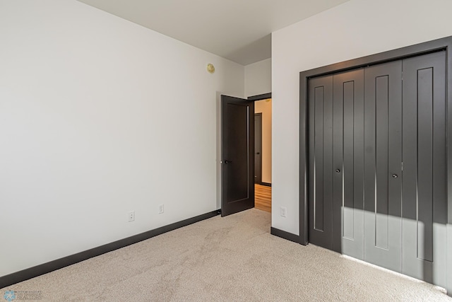 unfurnished bedroom featuring light carpet and a closet