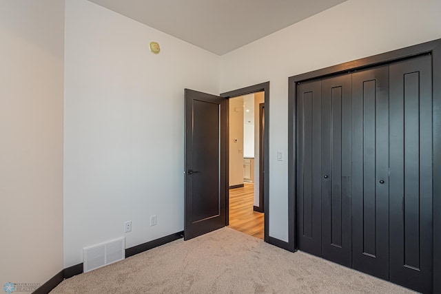 unfurnished bedroom with light colored carpet and a closet