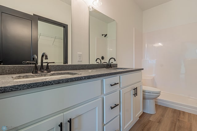 bathroom featuring vanity, wood-type flooring, toilet, and a shower