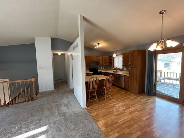 kitchen featuring lofted ceiling, decorative light fixtures, electric range oven, stainless steel dishwasher, and a kitchen breakfast bar