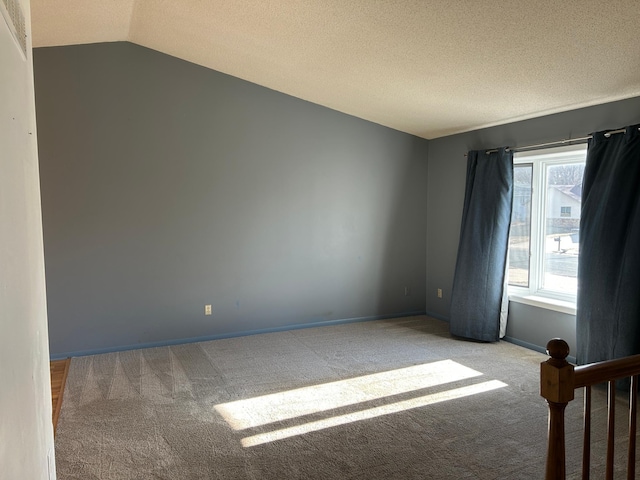 carpeted spare room featuring lofted ceiling and a textured ceiling