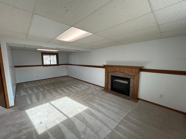 basement with a tiled fireplace, a paneled ceiling, and light colored carpet