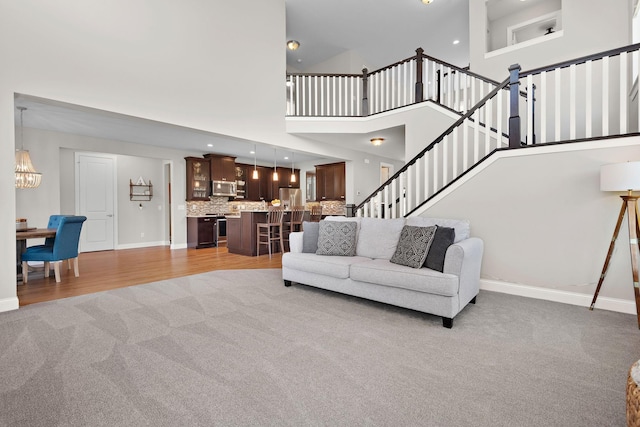 carpeted living room featuring a towering ceiling and a notable chandelier