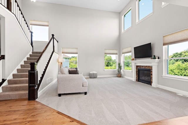 living room featuring a fireplace, light carpet, and a high ceiling