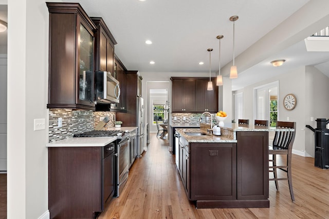 kitchen featuring appliances with stainless steel finishes, sink, decorative backsplash, and decorative light fixtures