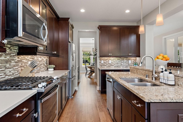 kitchen with pendant lighting, dark brown cabinetry, stainless steel appliances, and sink