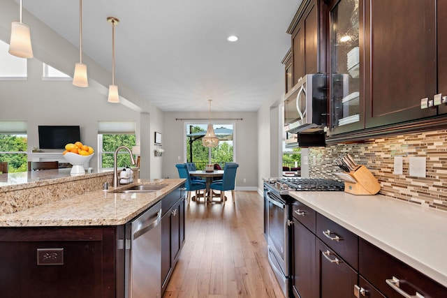 kitchen featuring dark brown cabinetry, sink, pendant lighting, stainless steel appliances, and backsplash