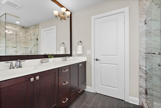 bathroom featuring vanity, an inviting chandelier, and a shower with shower door