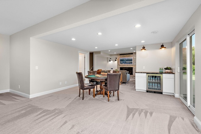 dining area featuring a fireplace, beverage cooler, and light carpet