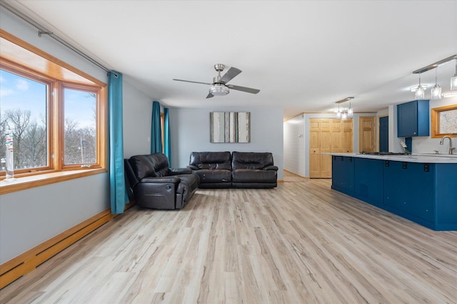 living room with sink, a baseboard radiator, ceiling fan, and light wood-type flooring