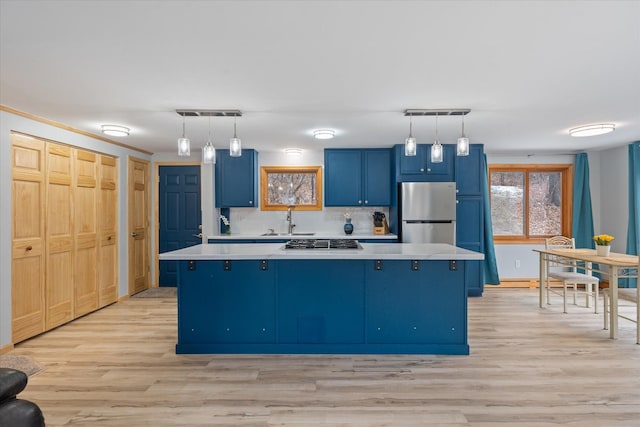 kitchen featuring blue cabinets, a kitchen island, appliances with stainless steel finishes, and decorative light fixtures