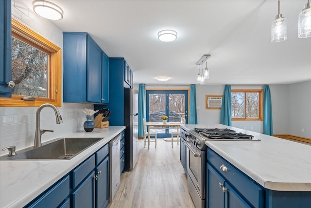 kitchen featuring blue cabinets, sink, hanging light fixtures, appliances with stainless steel finishes, and decorative backsplash