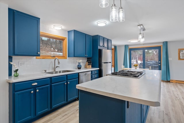 kitchen with appliances with stainless steel finishes, decorative light fixtures, blue cabinets, and a kitchen island