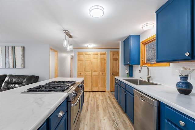 kitchen with sink, blue cabinetry, appliances with stainless steel finishes, backsplash, and light hardwood / wood-style floors