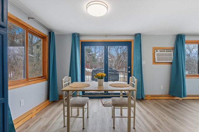 dining space with a wall mounted air conditioner, light hardwood / wood-style floors, and a wealth of natural light