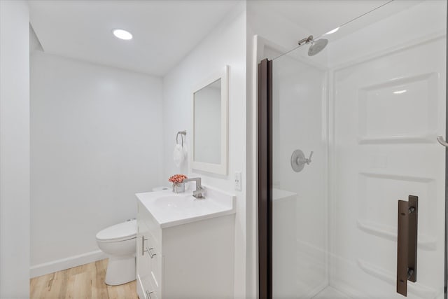 bathroom with wood-type flooring, toilet, vanity, and a shower with shower door